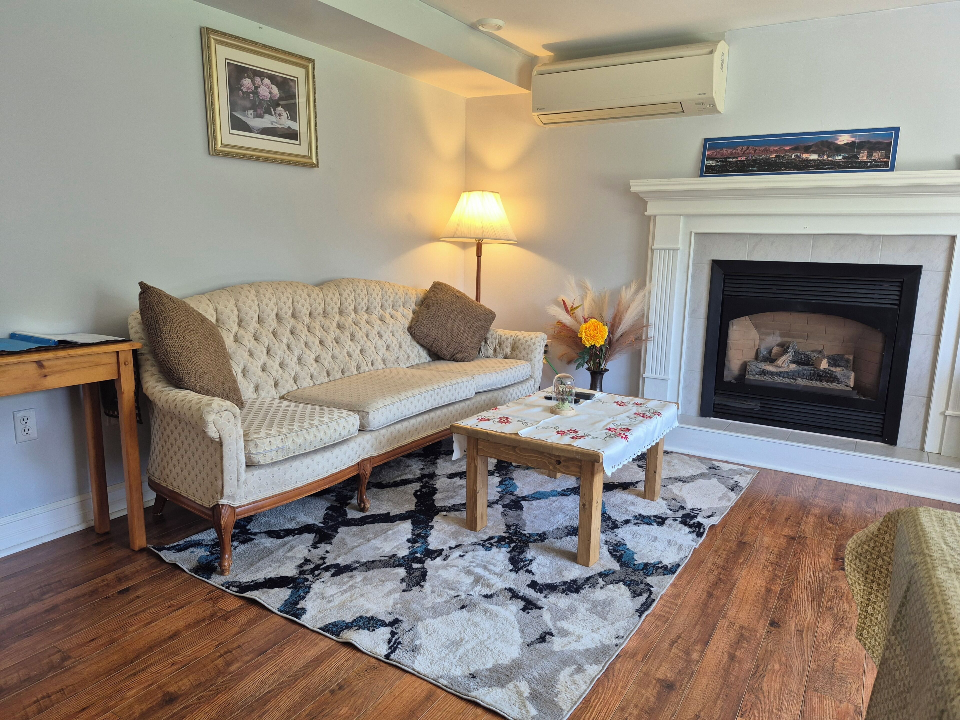 A living room with a sofa, a coffee table, a fireplace, and a lamp.