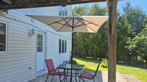A covered patio with a table and chairs, a large umbrella, and a wooden deck.