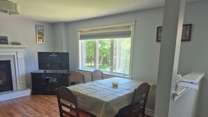 Uma sala de jantar com mesa, cadeiras, televisão e lareira.