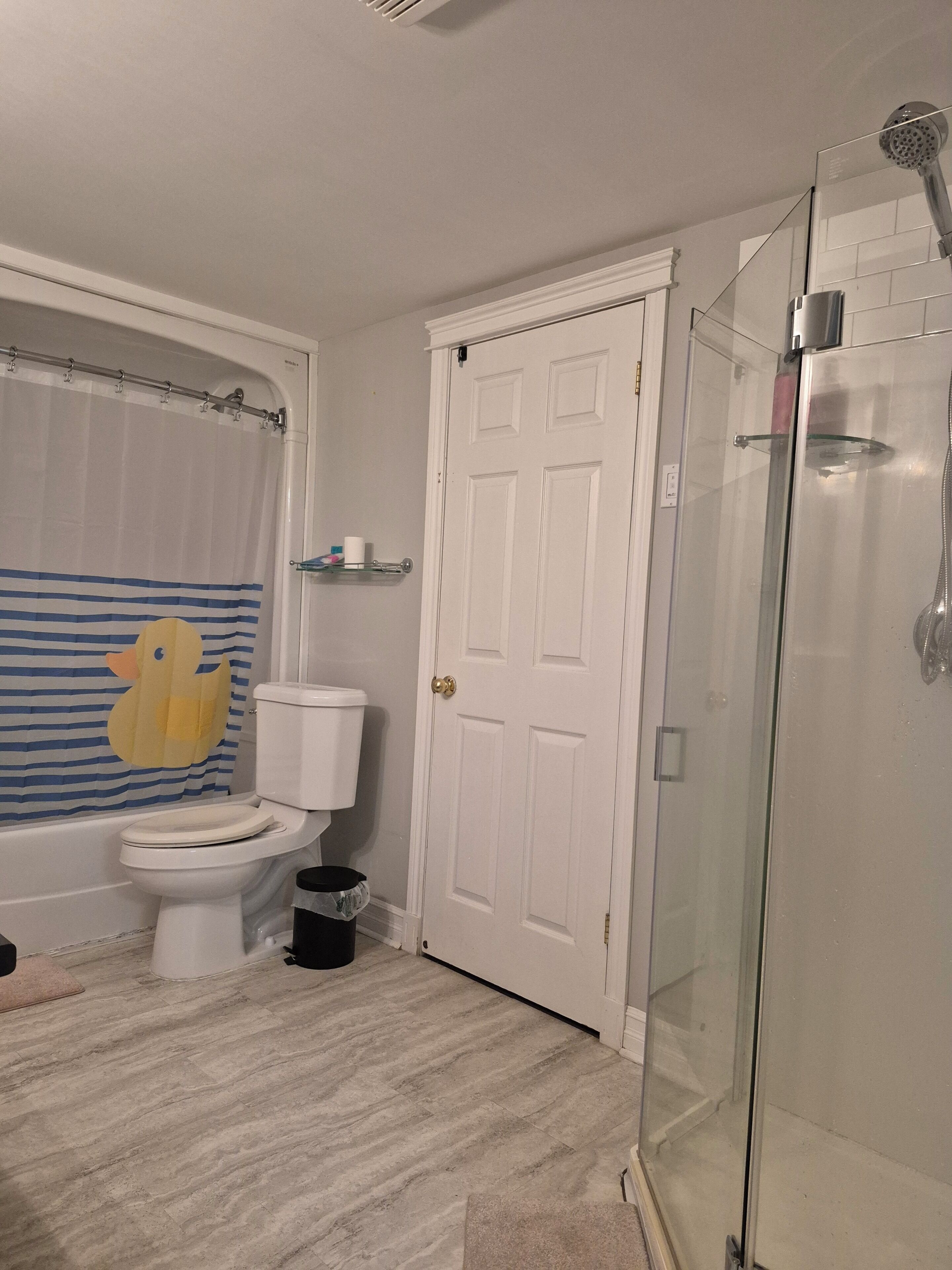 Un baño con inodoro, ducha y cabina de ducha de vidrio.