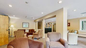 A hotel lobby with a reception desk, seating area with armchairs, and a carpeted floor.