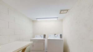 Ein Waschraum mit zwei nebeneinander gestapelten Waschmaschinen und Trocknern, einer Holzauskładung und einer Leuchtstofflampe.