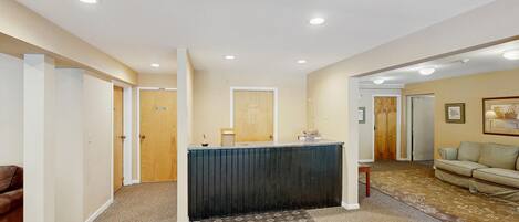A reception area with a counter, a patterned carpet, a sofa, and a door leading to another room.