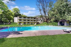 Un hotel con piscina, zona de estar exterior y un edificio con varios balcones.