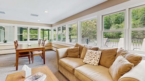 A spacious room with a large window, a dining table, and a sofa. - Four Season Condo: seasonal pool, ski, hike & golf (Warren)