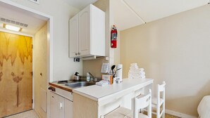 A compact kitchenette with a stove, sink, and cabinets.