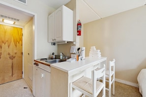 Una kitchenette compacta con estufa, lavabo y armarios.