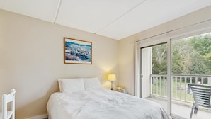 A hotel room with a bed, a nightstand, a lamp, and a view of the outdoors through a sliding glass door. - Four Season Condo: seasonal pool, ski, hike & golf (Warren)