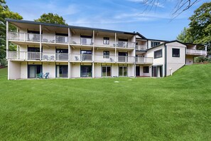 A multi-story building with balconies, a flat roof, and a well-maintained lawn. - Sugarbush Condo: seasonal pool, ski, hike & golf (Warren)