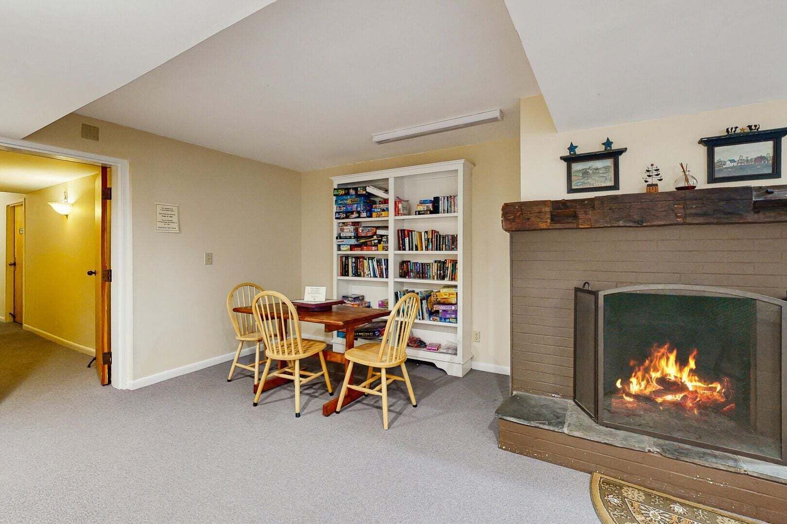 Una sala de estar con chimenea, una estantería y un comedor con sillas.