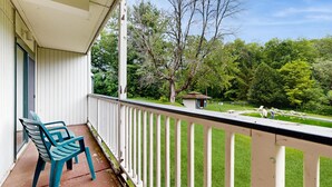 A balcony with two chairs, a small shed, and a pool area with lounge chairs. - Four Season Condo:  seasonal pool, ski, hike & golf (Warren)