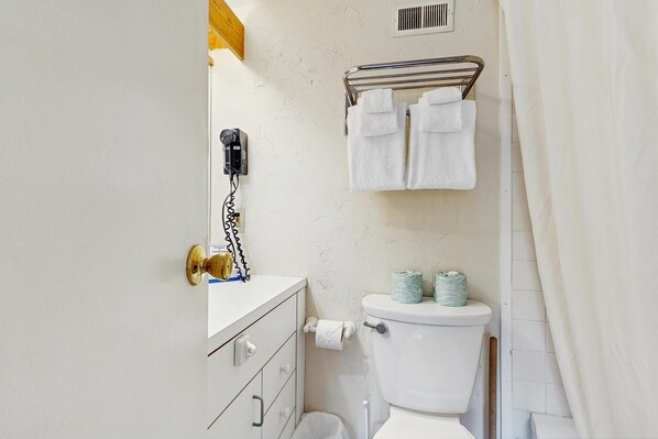 A bathroom with a toilet, a towel rack with towels, a hairdryer, and a toilet paper holder. - Four Season Condo: seasonal pool, ski, hike & golf (Warren)