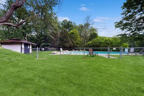 Un cortile recintato con piscina, un piccolo deposito e un prato erboso.