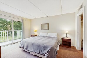 Una camera da letto con un letto grande, due comodini con lampade, una finestra vista su del verde e una porta che conduce a un armadio.