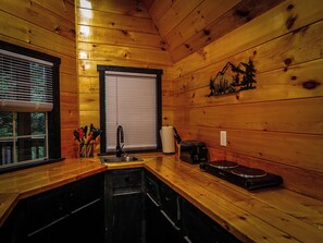 A compact kitchen with wooden walls, a sink, a toaster, and a window with blinds. - Escape to Black Bear Cabin near Red River Gorge, your private woodland retreat. (campton)