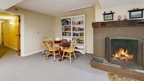 A room with a fireplace, a bookshelf, and a dining table with chairs. - Four Season Connecting Condos:  seasonal pool, ski, hike & golf (Warren)
