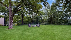 A well-maintained grassy lawn with two Adirondack chairs and a stone fire pit. - Four Season Connecting Condos:  seasonal pool, ski, hike & golf (Warren)