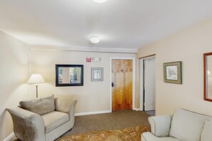 A hotel room with a sofa, a lamp, a door with a number, and framed pictures on the wall. - Four Season Connecting Condos:  seasonal pool, ski, hike & golf (Warren)