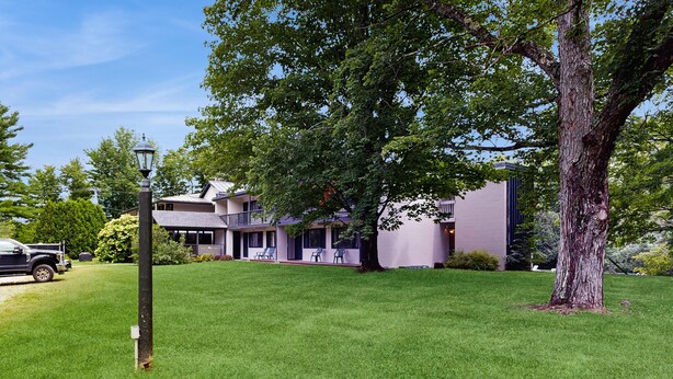 A residential area with a large tree, a street lamp, and a building with a balcony. - Four Season Connecting Condos:  seasonal pool, ski, hike & golf (Warren)