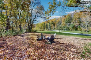 A park with a fire pit and Adirondack chairs on a leaf-covered ground. - Four Season Connecting Condos:  seasonal pool, ski, hike & golf (Warren)