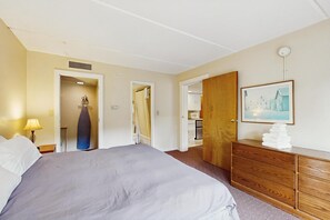 A hotel room with a bed, a dresser, a painting, and a shower area. - Four Season Connecting Condos:  seasonal pool, ski, hike & golf (Warren)