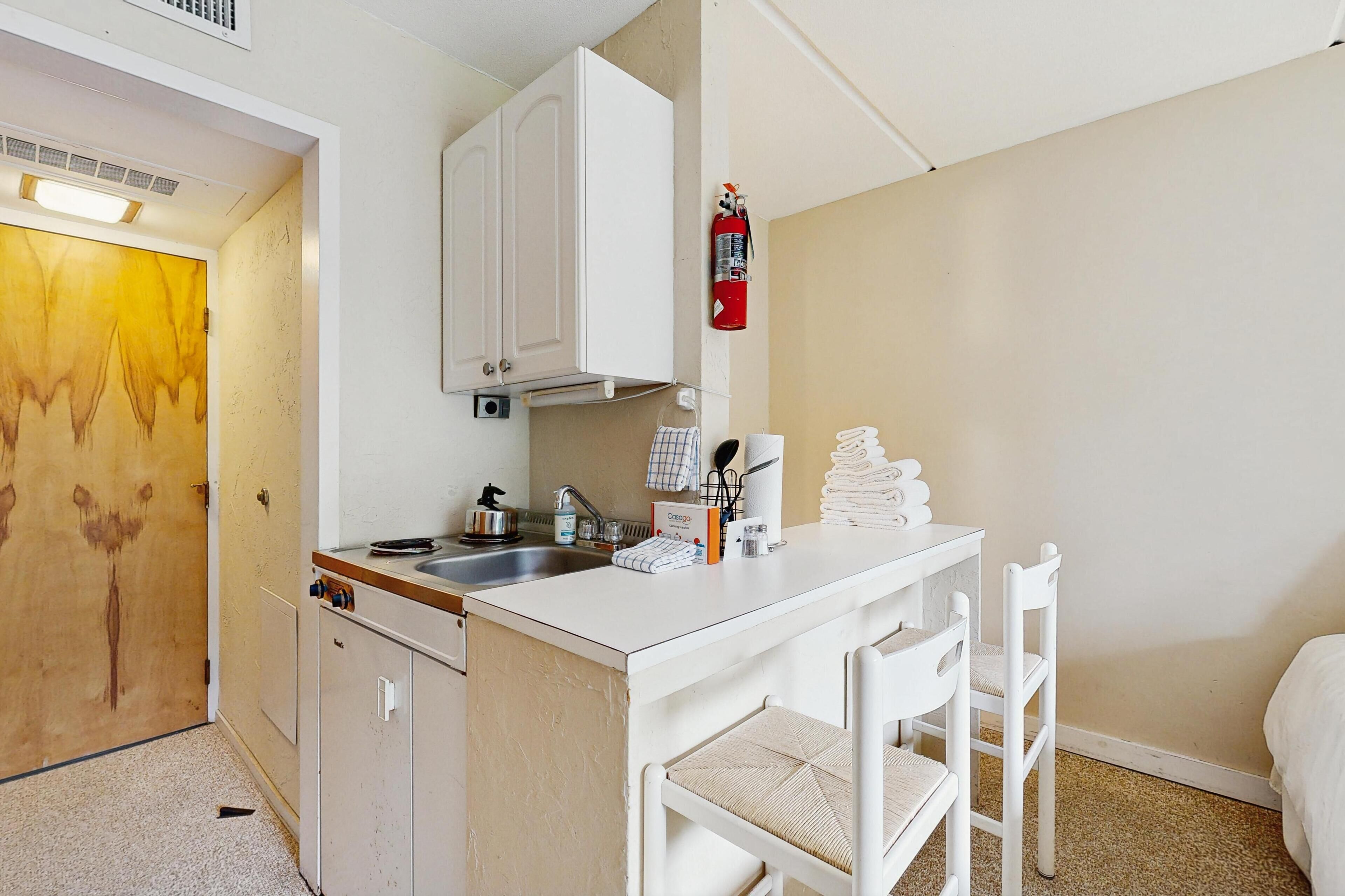Una kitchenette compacta con estufa, lavabo y armarios.