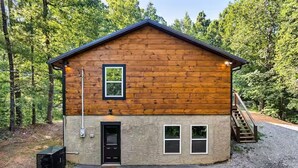 A wooden cabin with a front door, two windows, and a staircase leading to the upper level. - Endless MTN Escape: Spacious, Hot Tub, MORE GAMES! (Sevierville)
