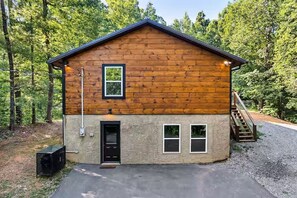 Eine Holzhütte mit einer Haustür, zwei Fenstern und einer Treppe, die zum Obergeschoss führt.