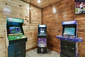 Three arcade gaming machines in a room with wooden walls and a ceiling. - Endless MTN Escape: Spacious, Hot Tub, MORE GAMES! (Sevierville)