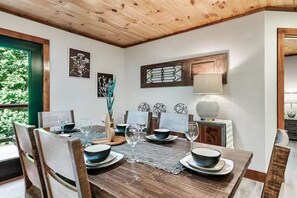 A dining area with a wooden table set for four, surrounded by chairs. - Endless MTN Escape: Spacious, Hot Tub, MORE GAMES! (Sevierville)