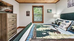 A bedroom with a bed, a dresser, a window, and a wall-mounted lamp. - Endless MTN Escape: Spacious, Hot Tub, MORE GAMES! (Sevierville)