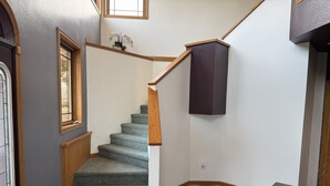 Eine Treppe mit Teppichstufen, Holzhandläufen und einer dunkel gefärbten Wand.
