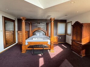 Une chambre à coucher avec un lit à baldaquin, une armoire en bois, un banc et une commode.