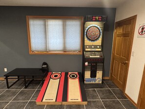A room with a dartboard, a table, and a window.