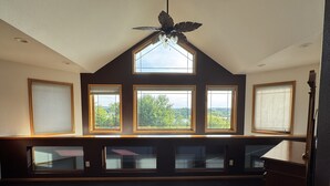 Ein Zimmer mit schrägverdeckter Decke, Dachfenster und mehreren Fenstern.