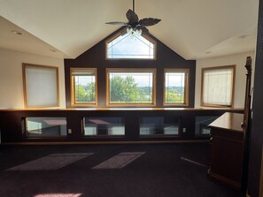 Ein Zimmer mit schrägverdeckter Decke, Dachfenster und mehreren Fenstern.