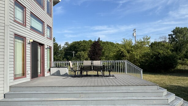 Eine Terrassenanlage mit Metallgeländer, einer Sitzbank und einer Treppe zu einer Tür.
