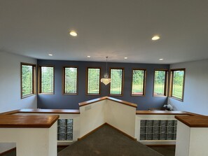A room with a sloped ceiling, multiple windows, and a chandelier.