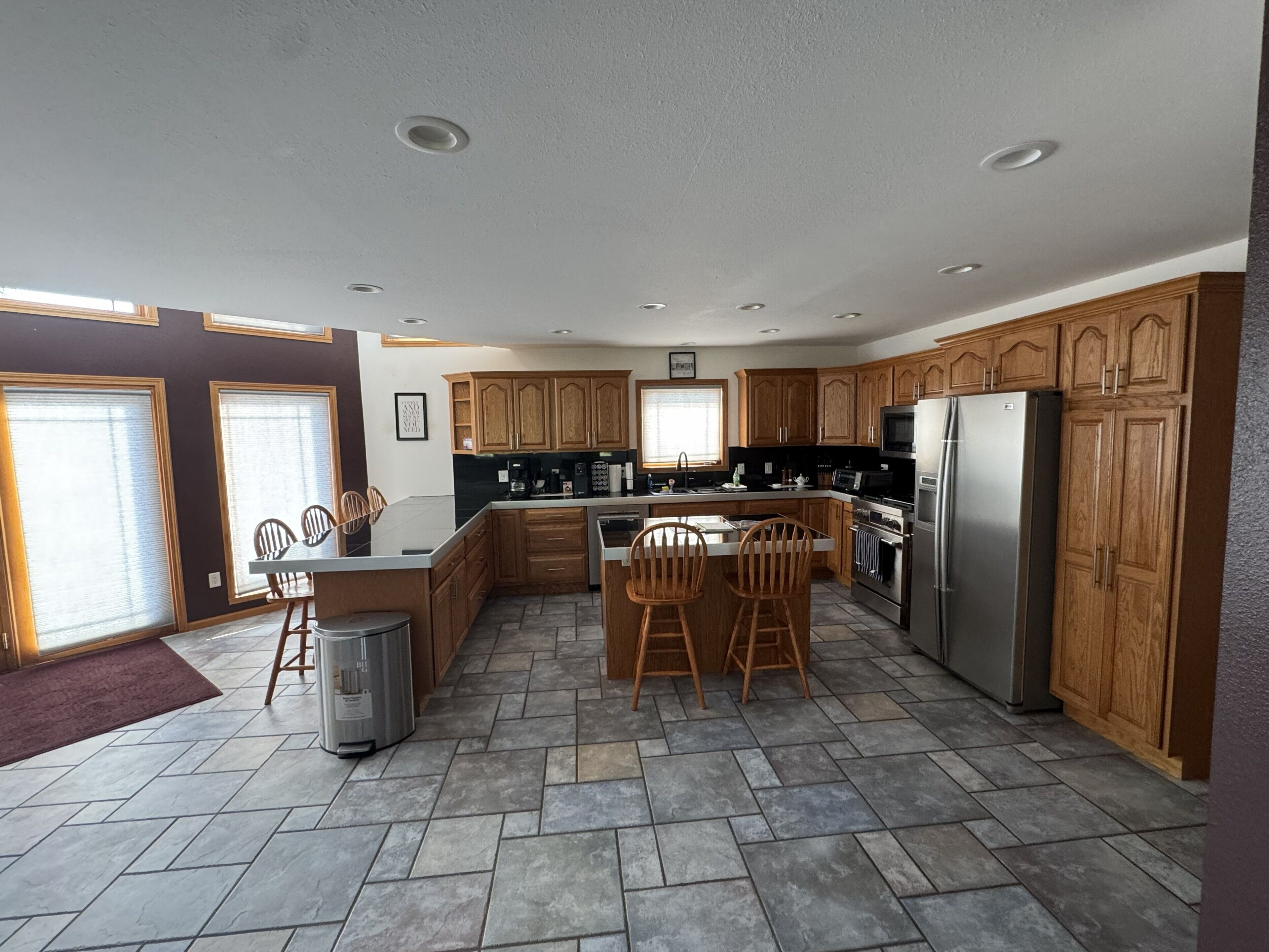 A modern kitchen with wooden cabinets, a central island, and stainless steel appliances.