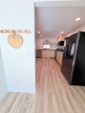 A modern kitchen with a black refrigerator, wooden cabinets, and a hanging basket.