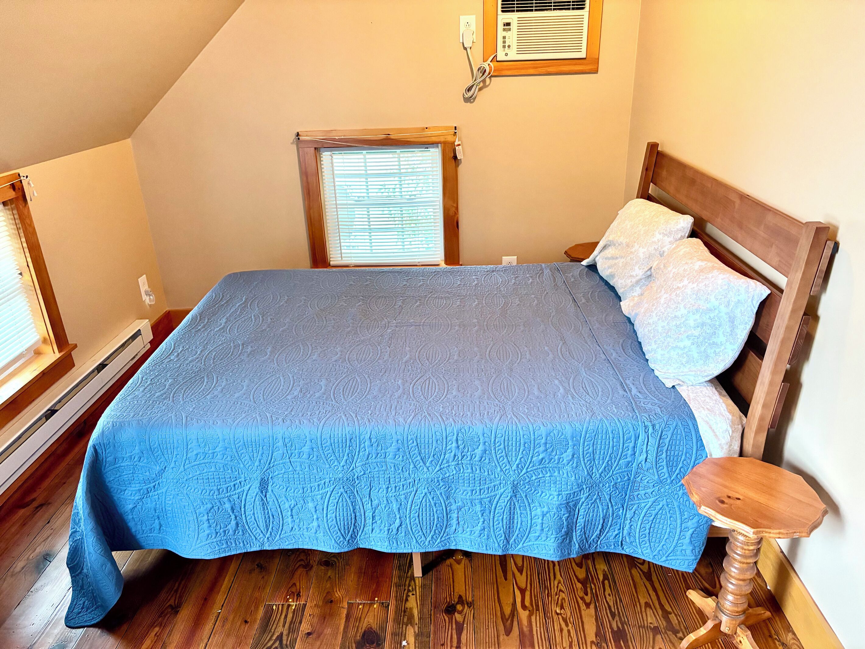 A bedroom with a bed, wooden headboard, and a small wooden table.