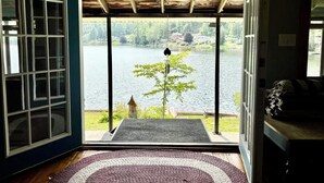 Une pièce avec vue sur un lac, un plafond en bois et une porte donnant sur l’extérieur.