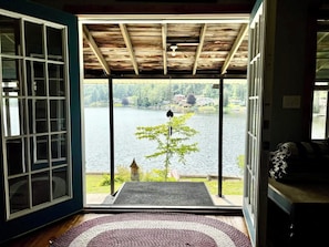 A room with a view of a lake, a wooden ceiling, and a door leading outside.