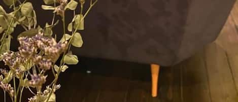Una habitación con sofá, una mesita, una planta y vistas a un jardín a través de una ventana.