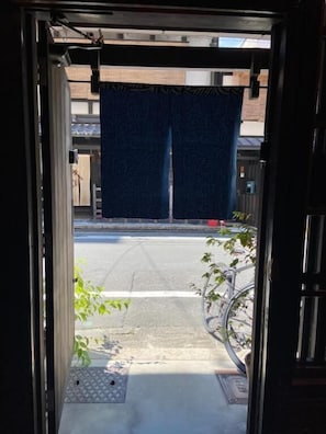 A doorway leading to a street with a bicycle parked outside. - Rokkon guest house (Kyoto)