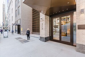 Um edifício moderno com uma entrada ampla, uma placa com o nome 'The Ellery' e o endereço visível '312 W 43'.