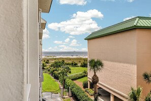 Blick vom Balkon auf einen Strand bei klarem Himmel und vereinzelten Wolken.