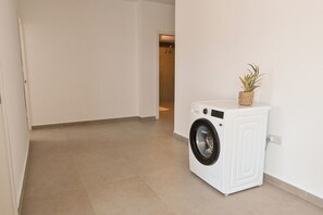 A laundry room with a washing machine and a potted plant. - Modern Seaside Apart in Marsalforn - 6B, Marsalforn Iz-Zebbug Gozo, Malta (Marsalforn Iz-Zebbug Gozo)