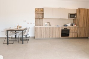 A modern kitchen with a dining area, featuring a built-in oven, microwave, and a small island with a sink. - Modern Seaside Apart in Marsalforn - 6B, Marsalforn Iz-Zebbug Gozo, Malta (Marsalforn Iz-Zebbug Gozo)