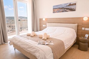Habitación de hotel con una cama grande, vistas de la ciudad y un cuadro en la pared.